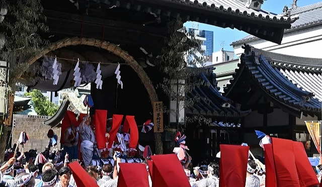 大阪天满宫天神祭活动现场,人群聚集进行传统仪式,抬神轿通过神社入口