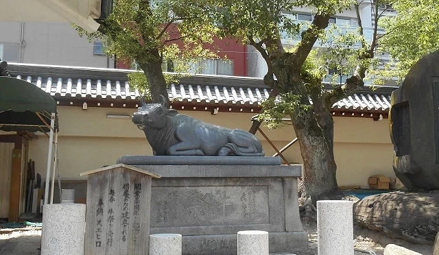 大阪天滿宮撫牛雕像，石座上臥牛造型，參拜者會觸摸祈求學業與身體健康