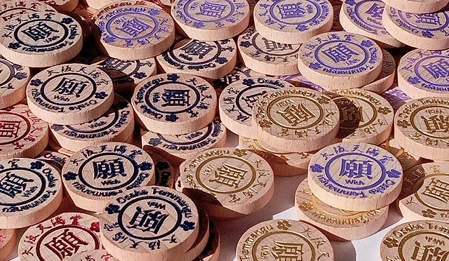 大阪天滿宮許願幣特寫，圓形木製硬幣印有不同顏色與圖案