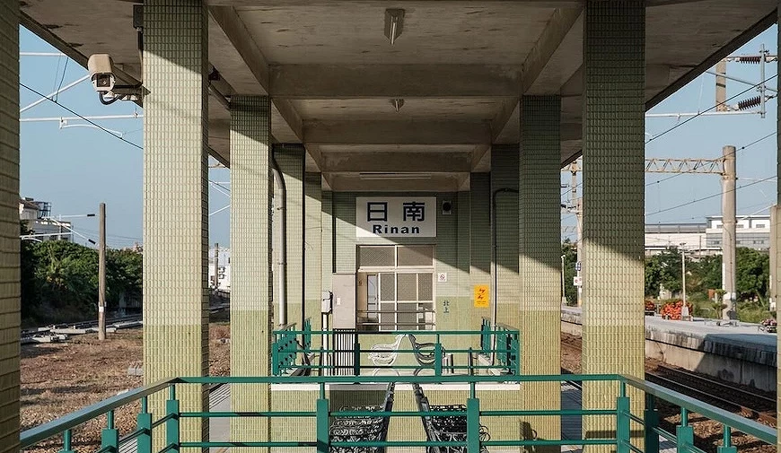 `台湾日南火车站月台,绿色磁砖柱与铁制座椅,站名标示「日南 Rinan」`