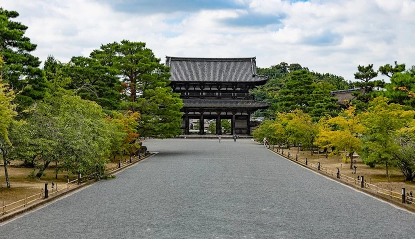 碎石步道通往傳統木造大門,兩側種有綠樹