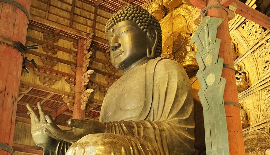 從側面仰望東大寺大佛殿內的奈良大佛(盧舍那佛),展現出佛像莊嚴的神態與一旁巨大的木造樑柱結構