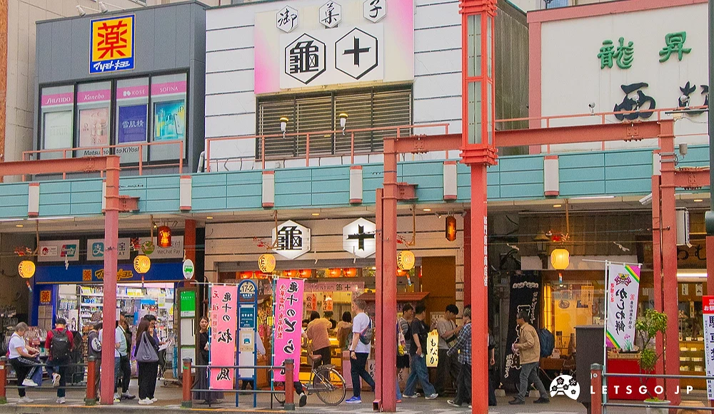 龜十與淺草街景 著名點心店「龜十」招牌醒目,前方設有公車站牌,人行道有旅客往來。