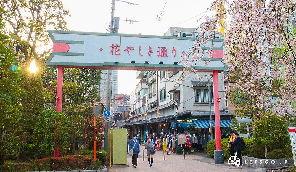 花屋敷通入口 花屋敷通商店街入口牌樓,周邊點綴著盛開的櫻花,街道兩側林立古舊店鋪。
