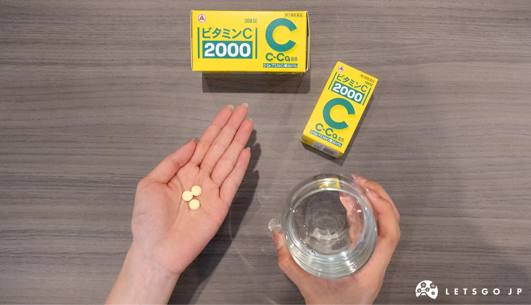 右手拿水杯,左手心放三顆維他命C