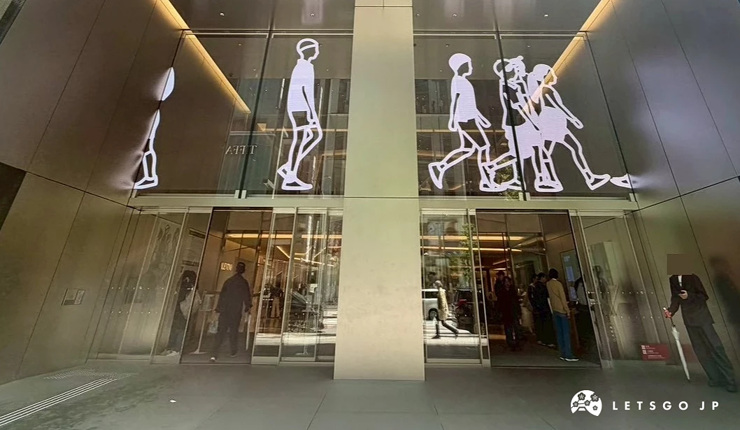GINZA SIX 挑高大門，玻璃帷幕上的 Julian Opie 藝術發光人像與銀座街景重疊。