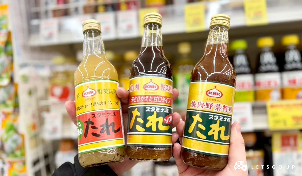 一隻手同時拿著三瓶不同款式的KNK源醬燒肉醬玻璃瓶,從左至右分別為鹽味、低敏款與經典原味款。