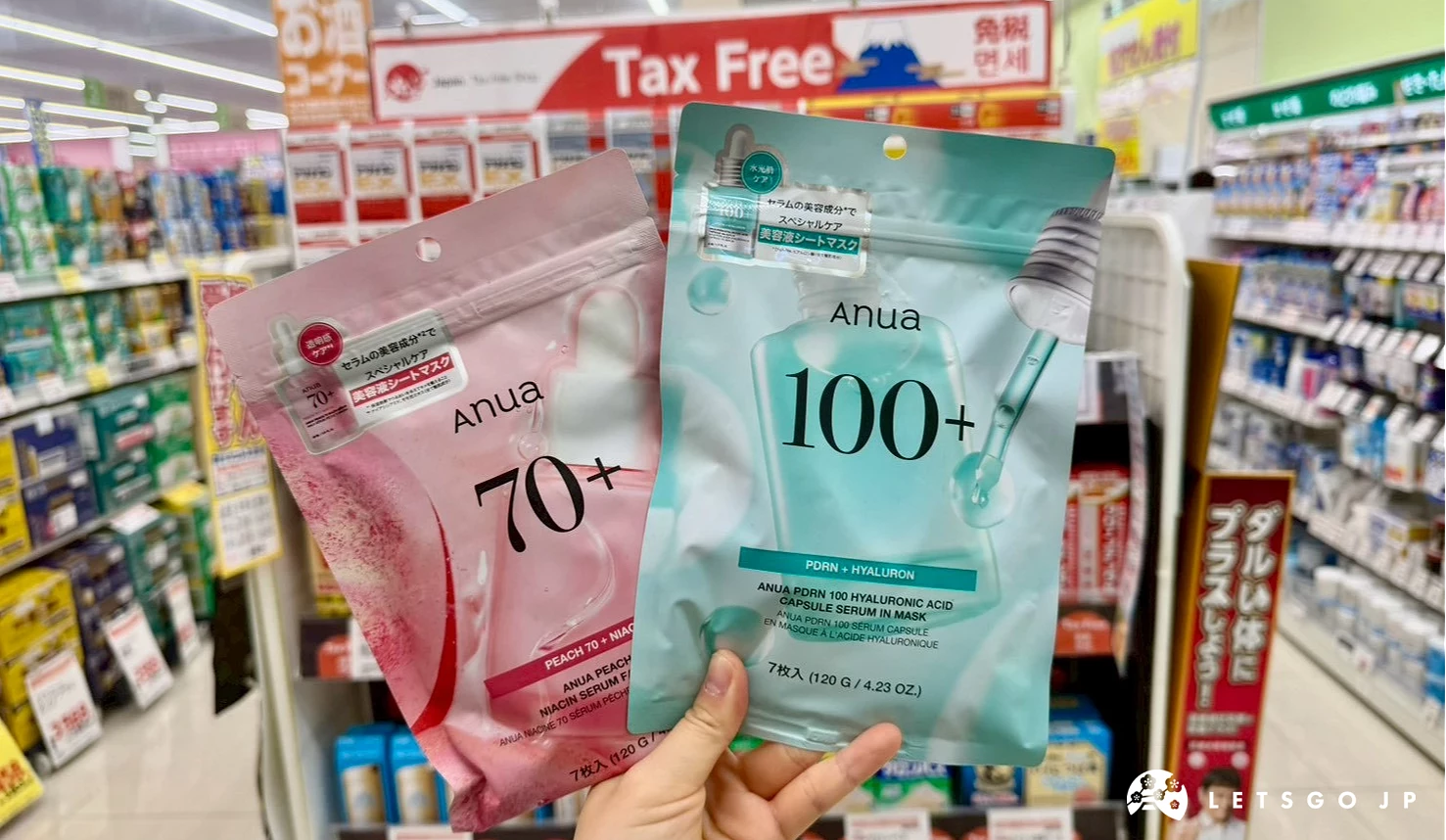 一隻手在免稅櫃檯前同時展示韓國Anua粉色桃子美白面膜與藍綠色玻尿酸保濕面膜,背景有免稅標誌。