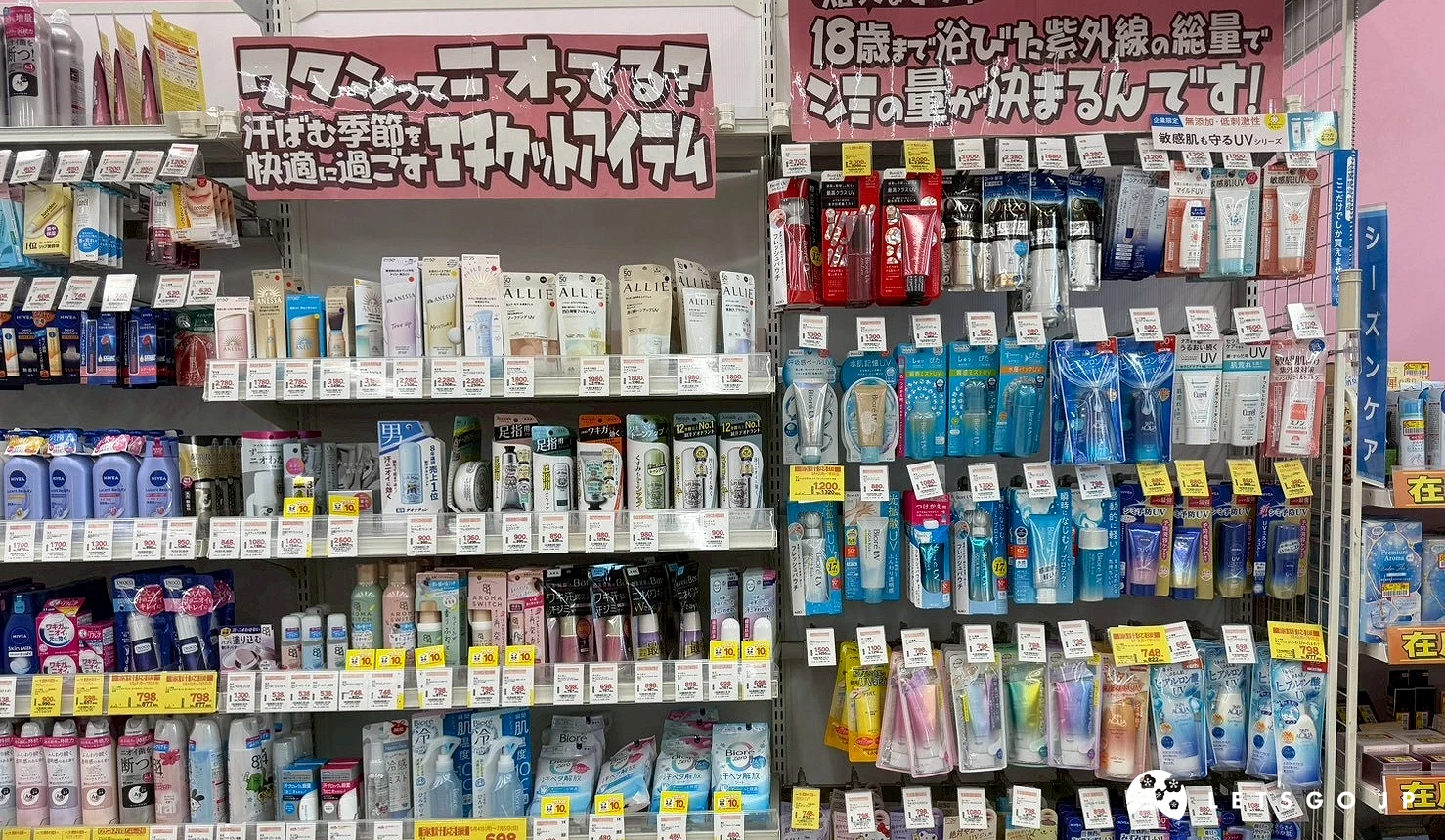 藥妝店內琳瑯滿目的個人護理與美妝工具層架,商品擺放密集且分類整齊,上方有粉紅色推薦看板。