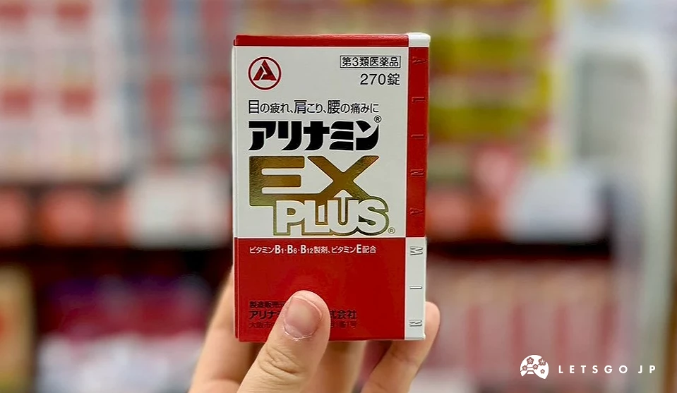 一隻手在藥妝店內拿著一盒紅色包裝的合利他命 EX PLUS 強效錠,背景為模糊的保健食品層架。