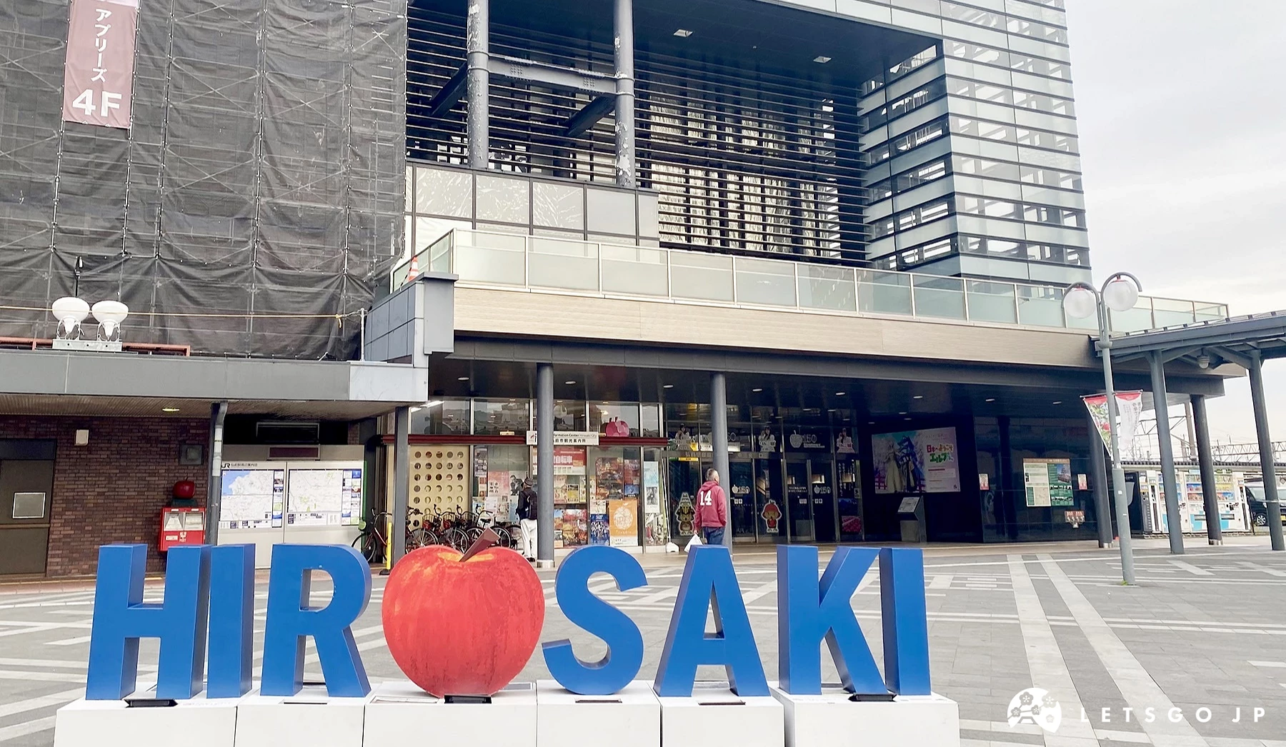 弘前車站外觀,前方廣場設有紅色蘋果圖樣與藍色「HIROSAKI」英文字樣的英文字體裝置藝術。