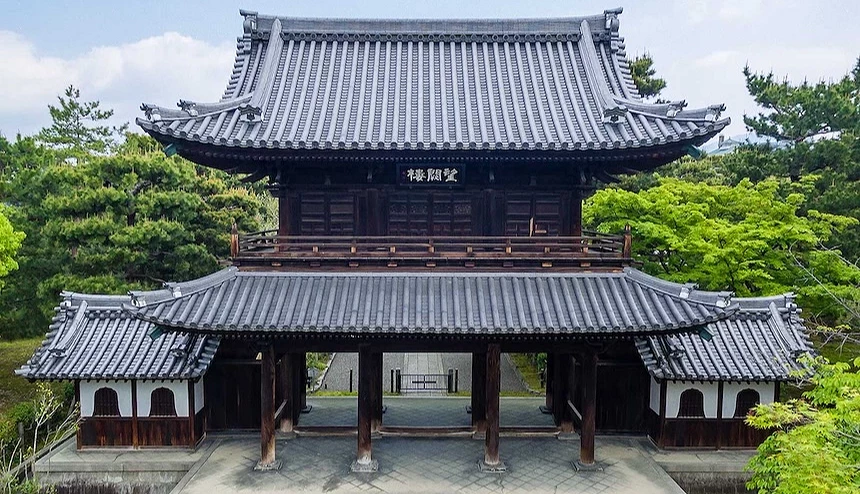 兩層樓高的傳統日式木造山門，周圍被綠樹環繞