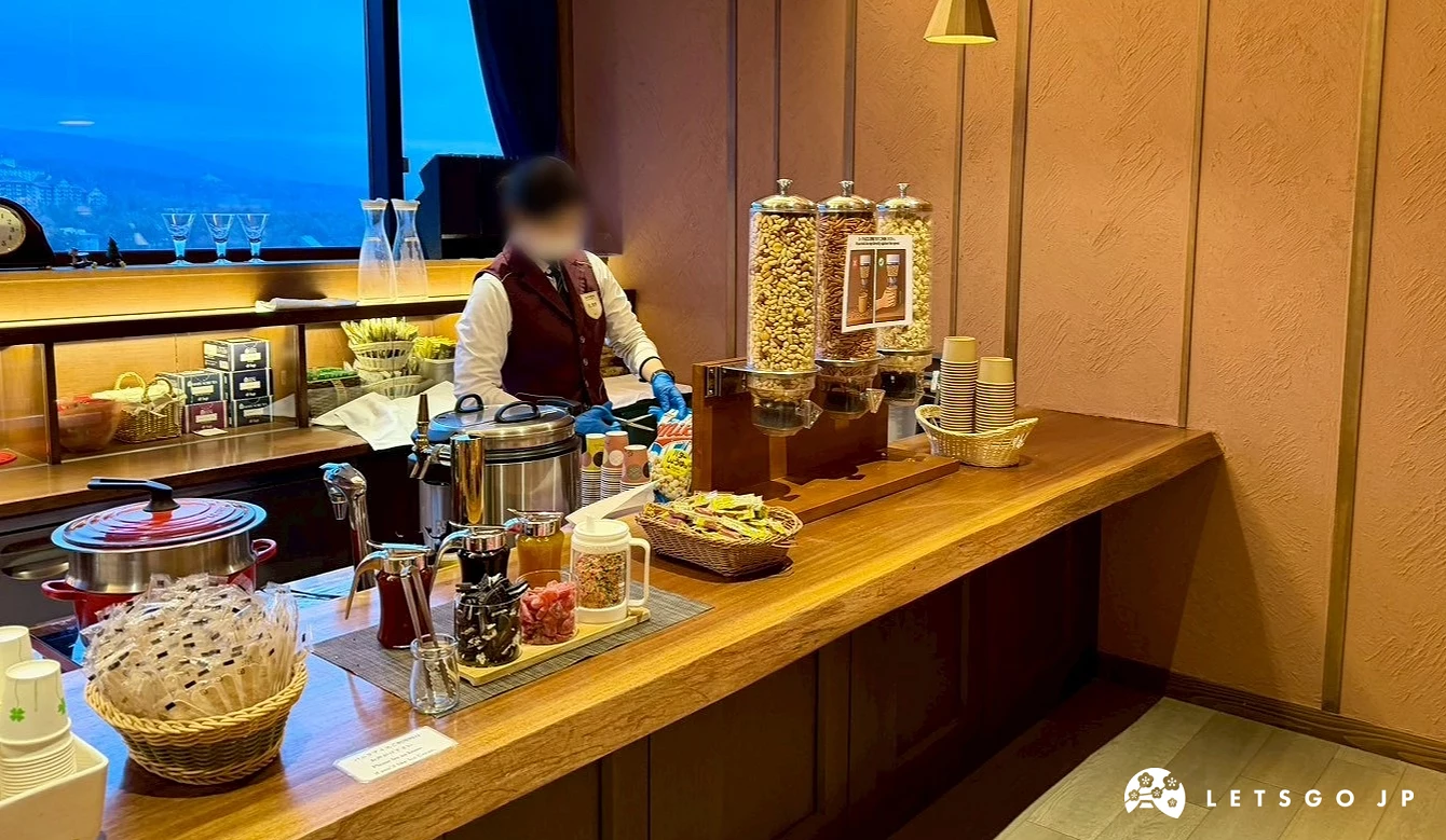 Lounge 內的長型木質吧台,擺放著咖啡機、飲料壺與多種零食餅乾。