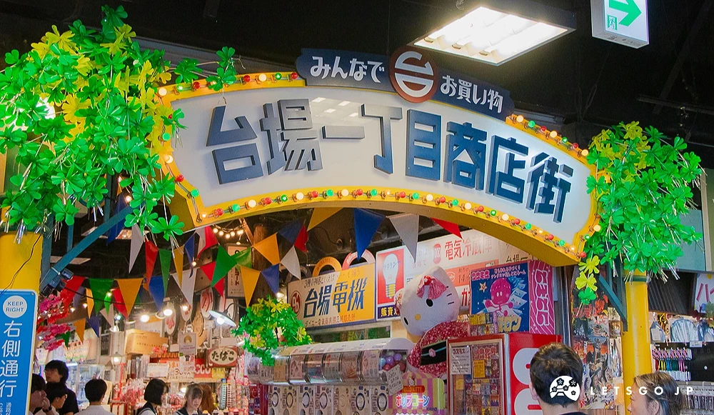 台場一丁目商店街 台場一丁目商店街復古招牌,周邊裝飾綠色植物與各色三角旗幟。
