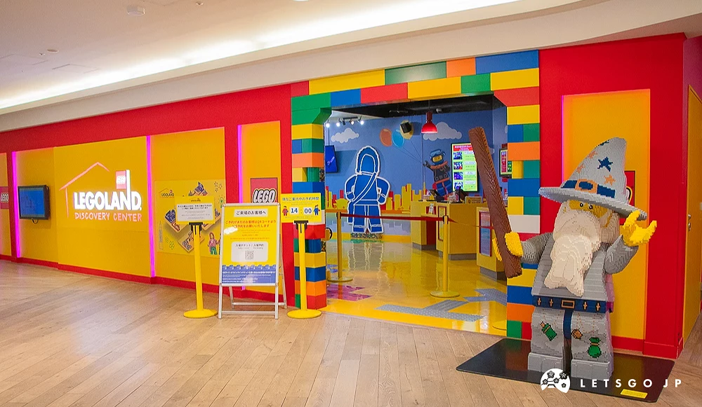 樂高樂園探索中心 LEGOLAND 鮮豔紅黃彩繪牆面入口,右側立有大型樂高積木巫師模型。