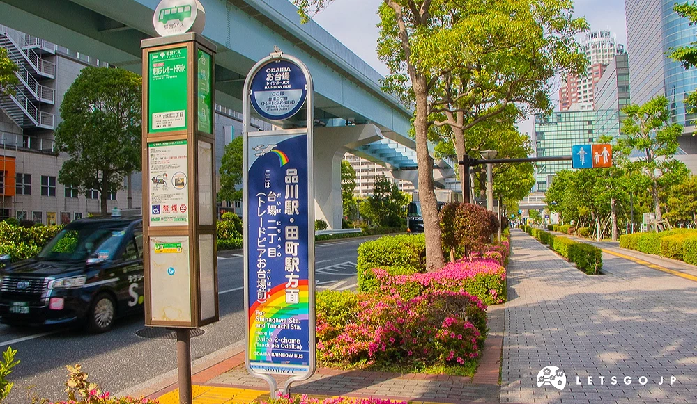 台場二丁目巴士站 人行道旁設有都營巴士與彩虹巴士站牌,前方有黑色計程車駛過。
