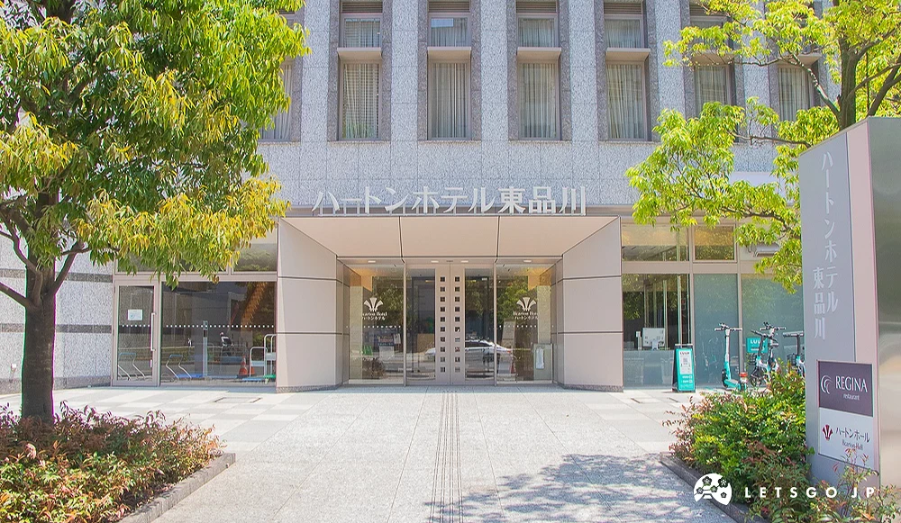 ハートンホテル東品川入口 Hearton Hotel 飯店灰色外牆正門,門口兩側種植綠色樹木。
