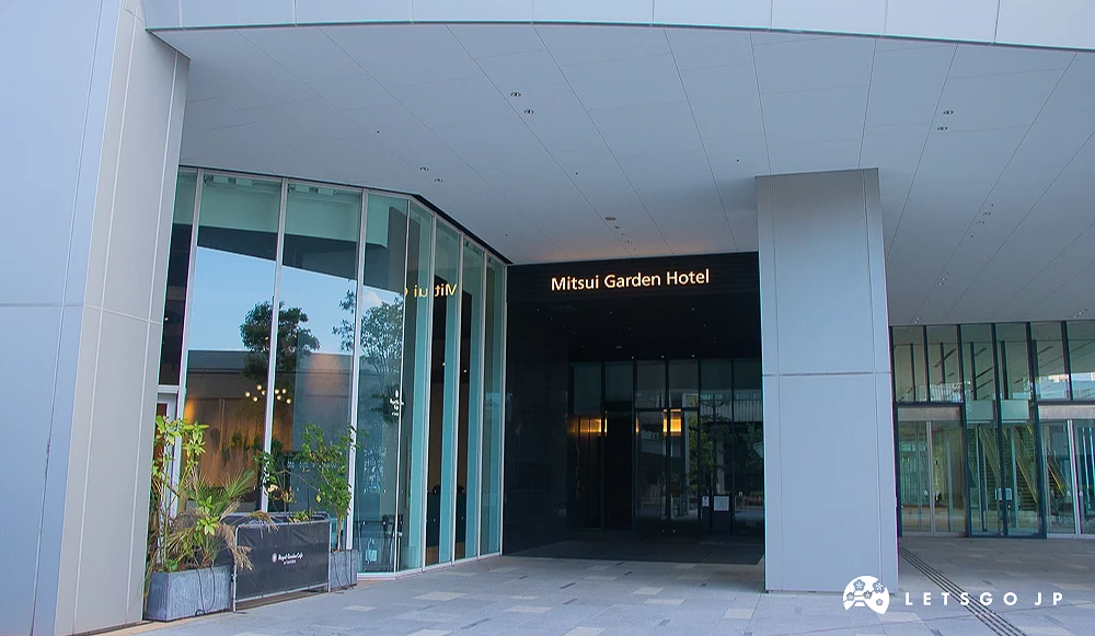三井花園飯店入口 三井花園飯店大門挑高遮棚,牆面嵌有發光的「Mitsui Garden Hotel」英文字樣。