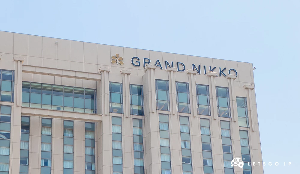 東京台場日航大酒店大樓頂端,牆面設有金色花瓣標誌與藍色「GRAND NIKKO」品牌字樣。