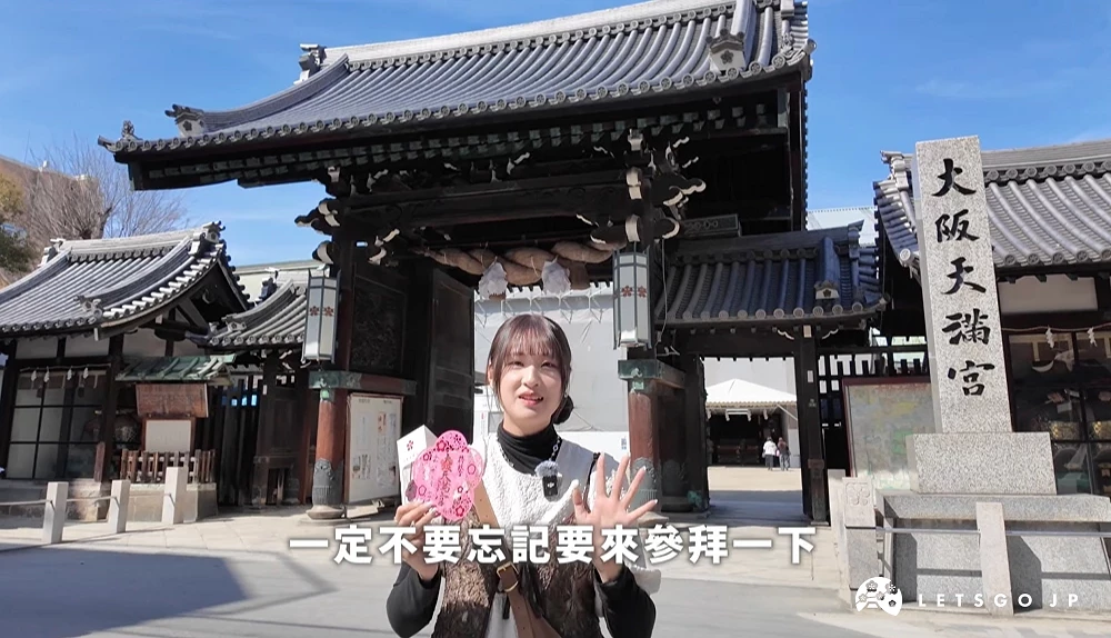 主持人站在大阪天滿宮門口介紹