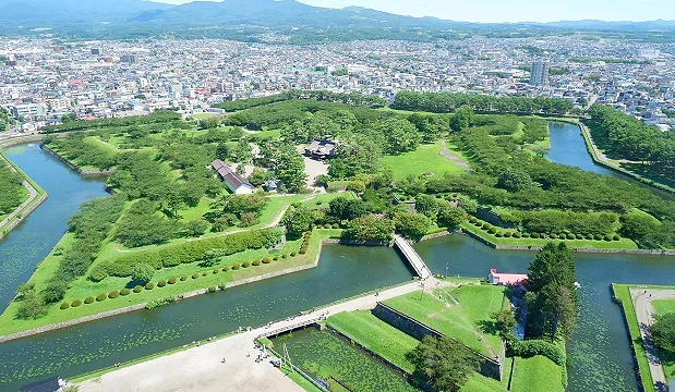 日本北海道函馆五棱郭公园空拍景色,可见星形城郭遗迹、护城河、绿地与周边市街,夏季绿意盎然,是函馆代表景点之一