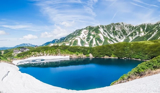 立山黑部室堂周边夏季山岳景色,湛蓝湖泊映照北阿尔卑斯群山,残雪、绿意与蓝天交织,展现高海拔地区清凉壮阔的自然风光