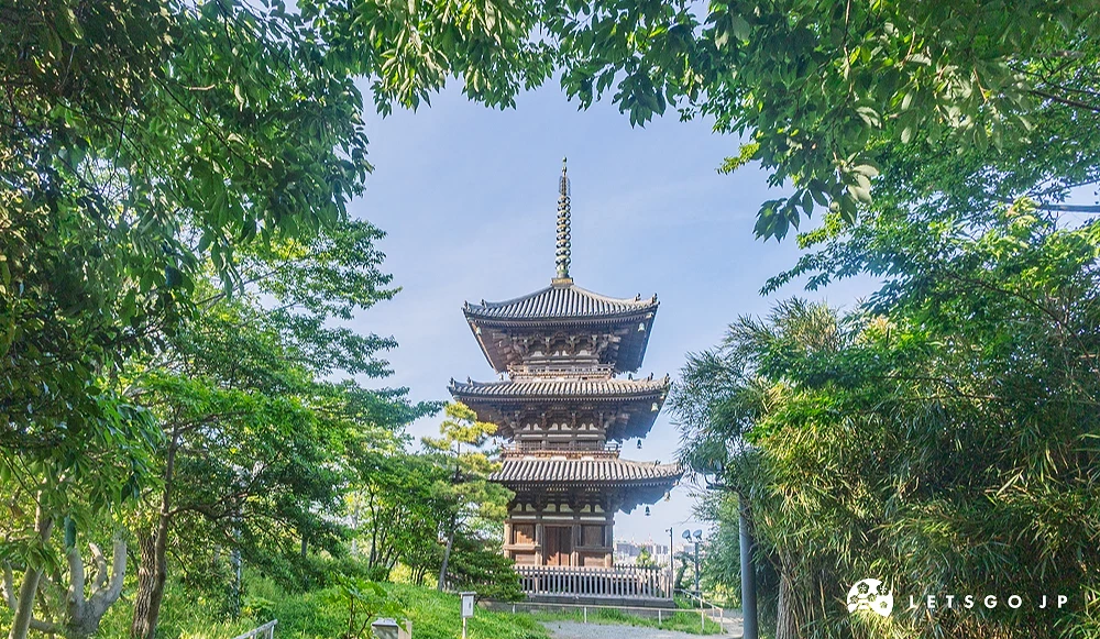 被綠色樹木框住的三重塔,後面是清澈的藍天