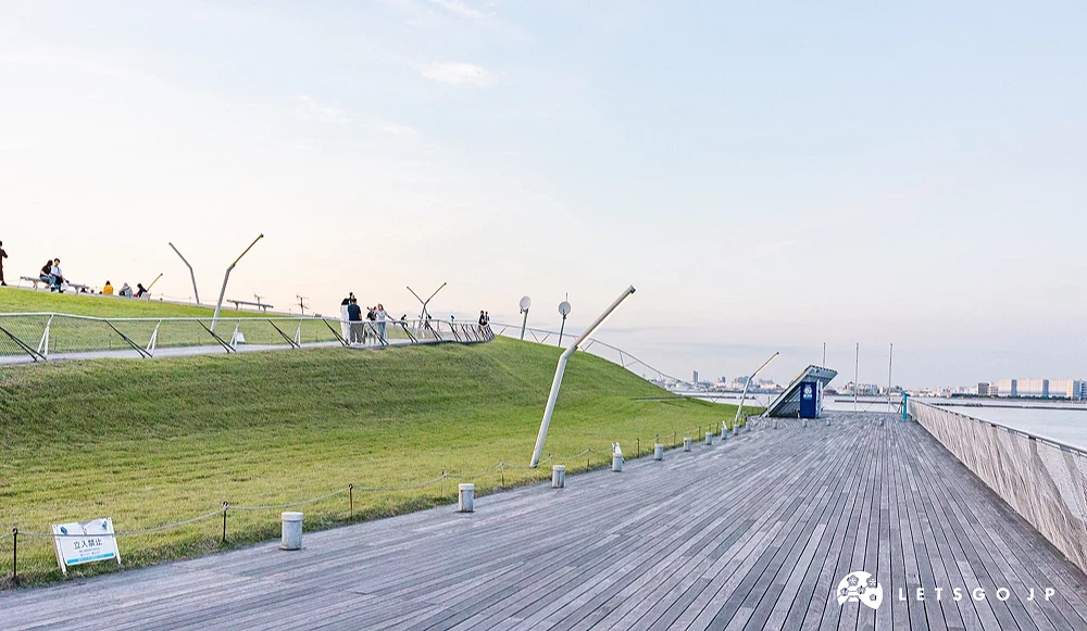 往上走的道路旁有草地,木頭地板路上旁邊則是漂亮的海