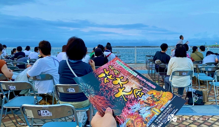 坐在海边座椅,手拿花火大会宣传单