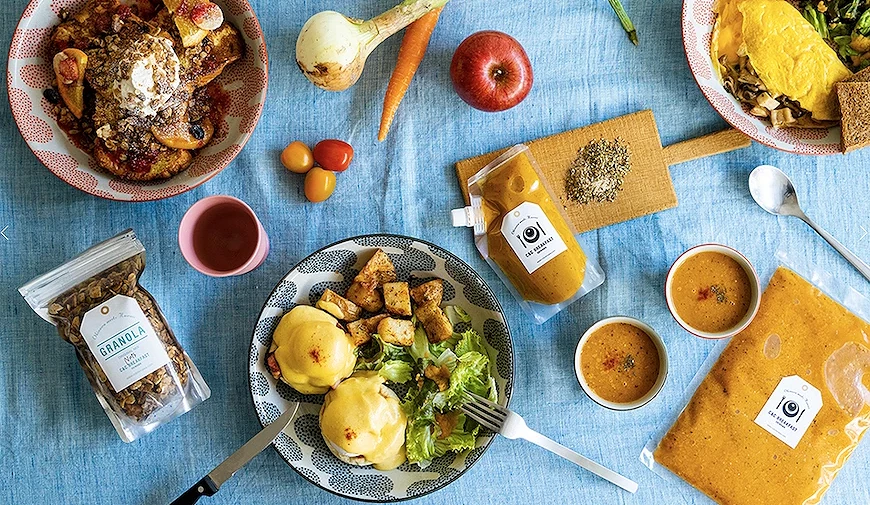 俯視早午餐食材與成品擺盤，含班尼迪克蛋、歐姆蛋、法式吐司、granola 及寫有日文標語的醬料包