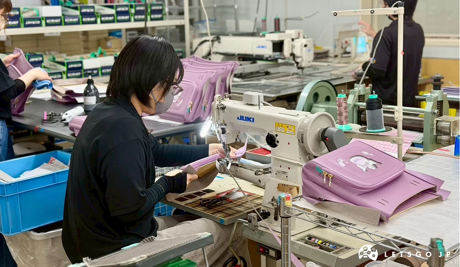 工廠內工作人員操作縫紉機製作日本小學生書包。