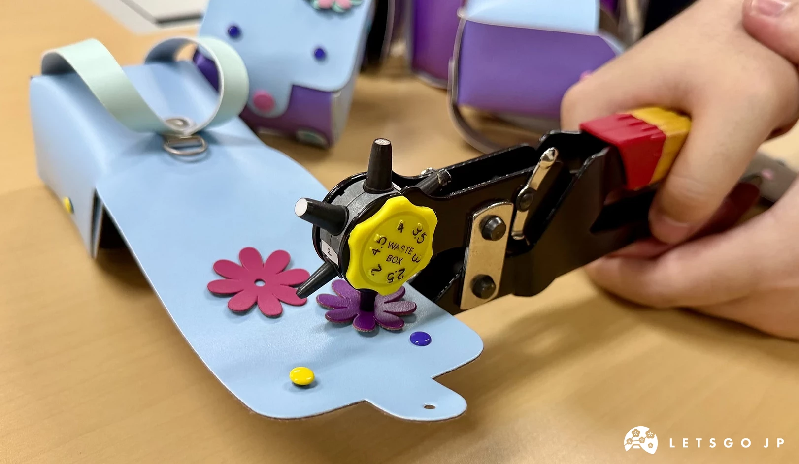 使用工具將花朵裝飾固定在迷你日本書包DIY材料上。