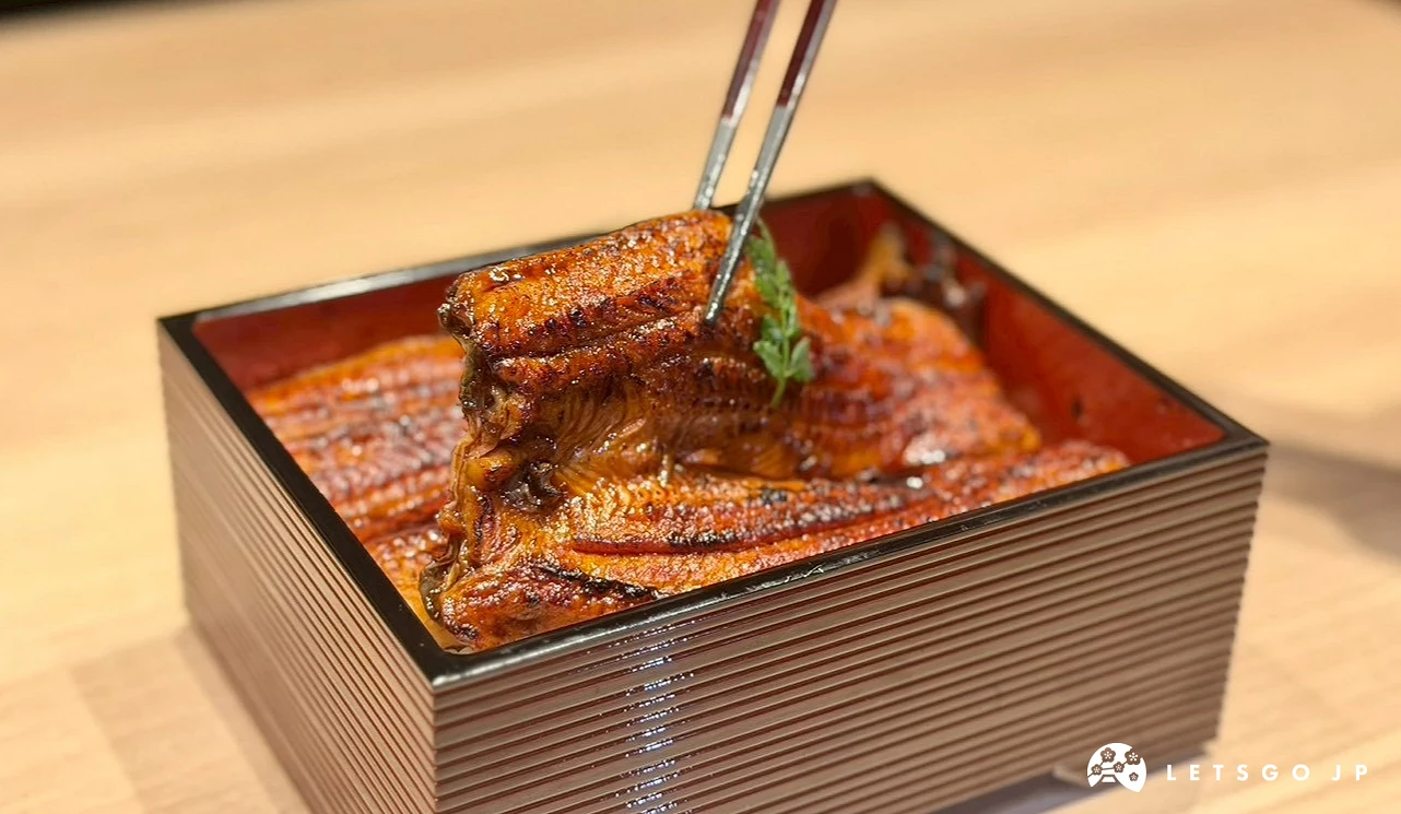 用筷子夾起鋪在白飯上、沾滿濃郁甜鹹醬汁的肥美蒲燒鰻魚,肉質看起來極其細緻柔軟。