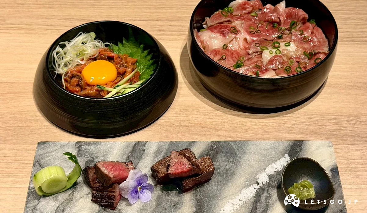 奢華的頂級牛肉盛宴,前方是用長條石盤精緻擺盤的厚切炙燒仙台牛,後方右邊是鋪滿鮮美肉片的神戶牛丼飯,後方左邊則是盛裝在黑碗中的神戶牛生蛋拌牛肉。