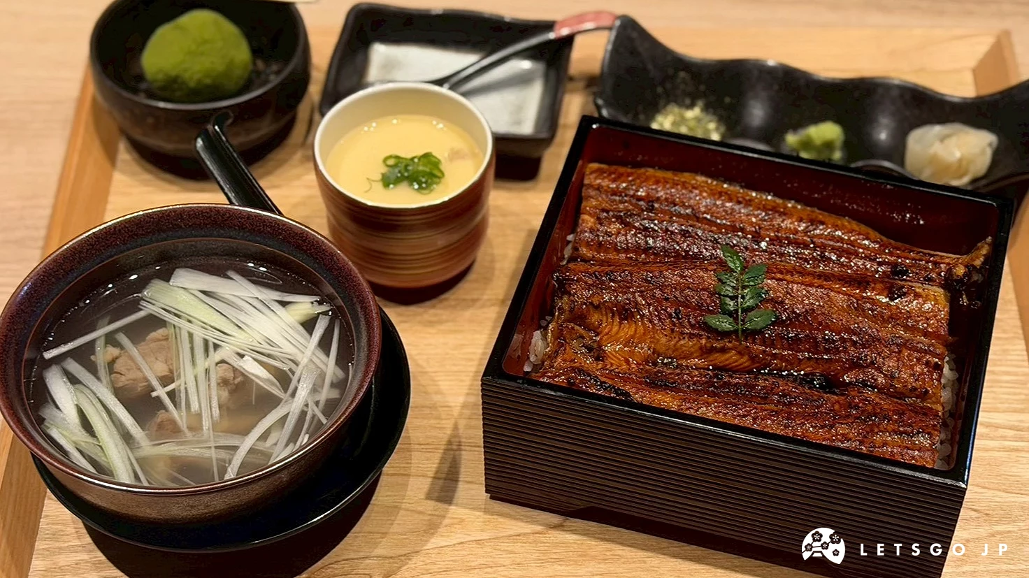 鰻魚重御膳豐盛組合,漆器方盒內鋪滿肥美焦香的蒲燒鰻魚飯,身旁附上茶碗蒸、青蔥牛尾湯與一小碗抹茶大福。