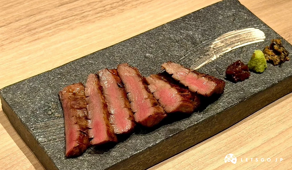 石質長盤上整齊排列的炭烤和牛牛舌特寫,切面透出微帶粉嫩的完美熟度,邊緣微焦,身旁附有特色沾醬與漬物。