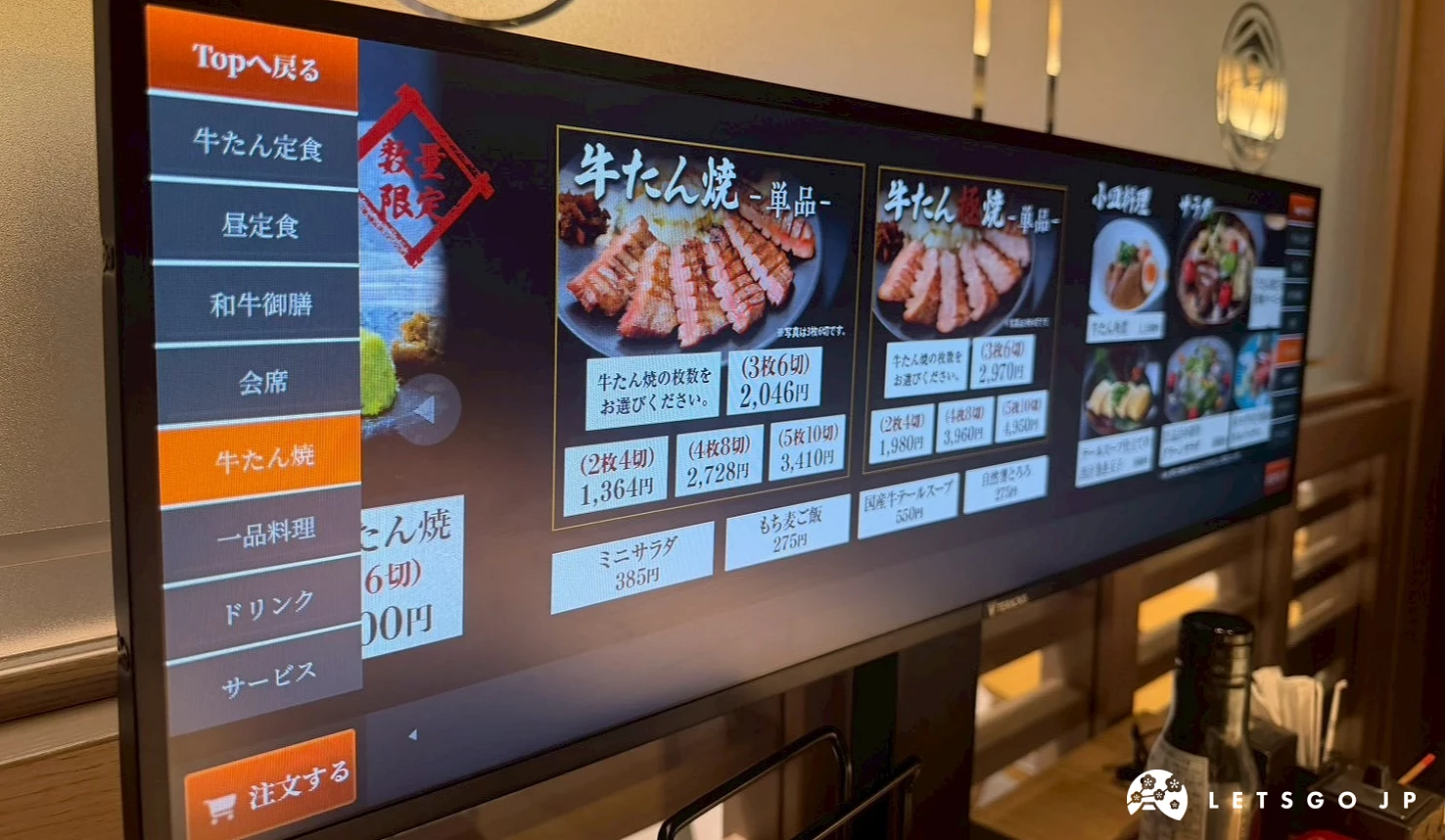 電子菜單螢幕,清晰展示著各式炭烤牛舌定食、和牛料理與華麗御膳的彩色圖片與價格資訊。