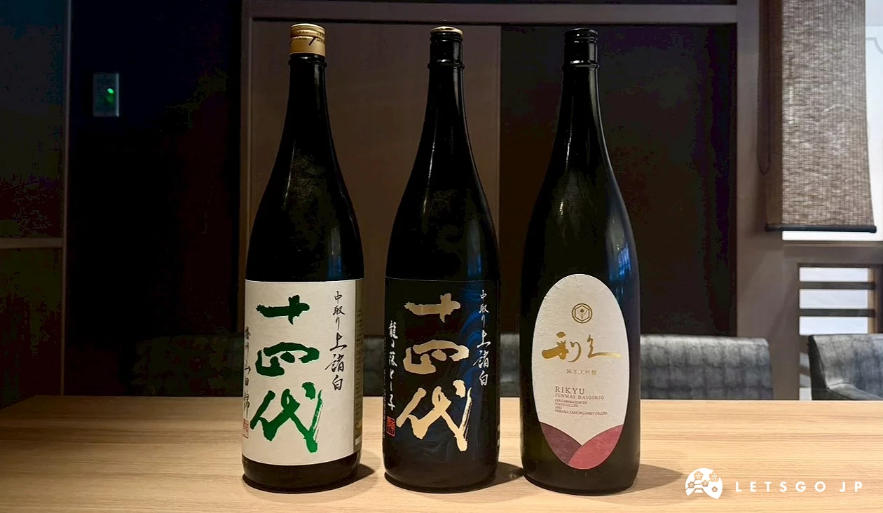 木質桌面上整齊排列的三款高級清酒瓶,包含知名日本酒「十四代」與利久純米大吟釀,展現優雅精緻的清酒選品。