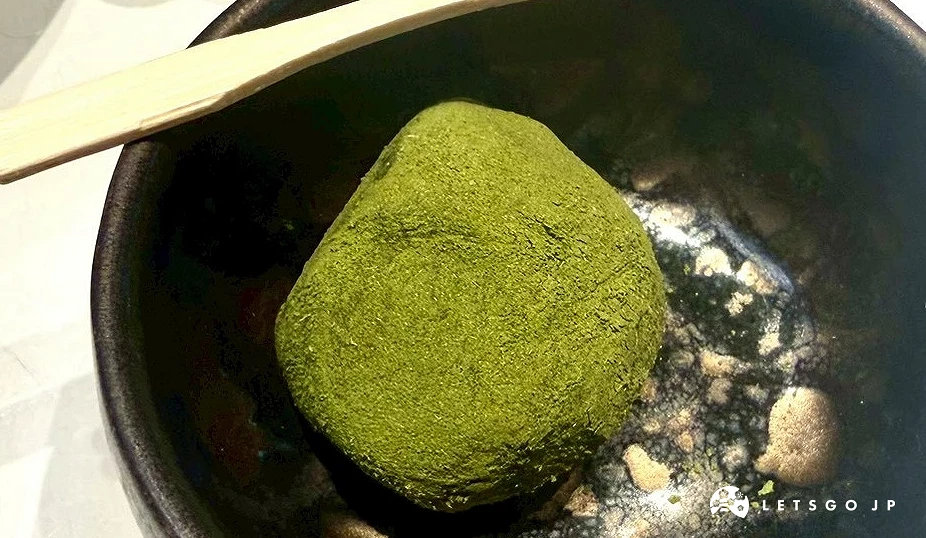 盛裝在黑色陶碗中的抹茶紅豆大福特寫,外皮裹滿翠綠細緻的抹茶粉,呈現柔軟Q彈的誘人質地。