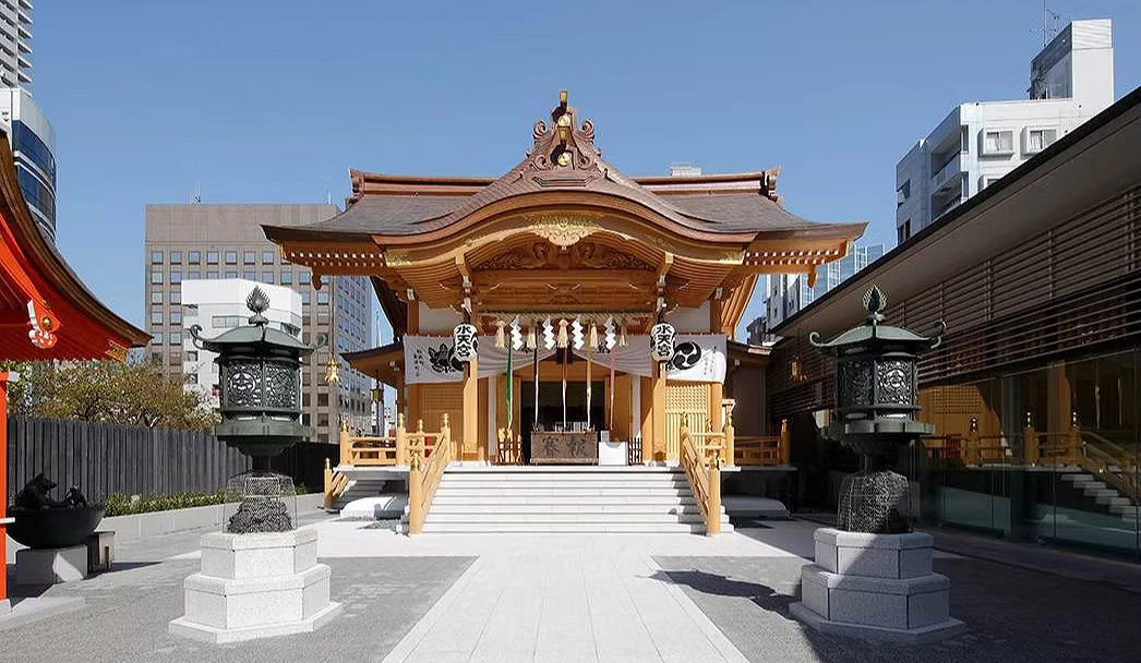 一座金色的寺廟在中間,左右有石燈和石頭道路,後面是高樓大廈