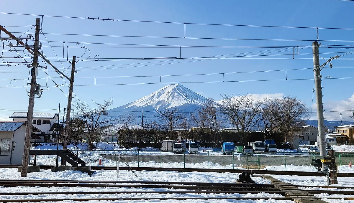 背景为蓝天和富士山,前景为覆盖白雪的铁轨