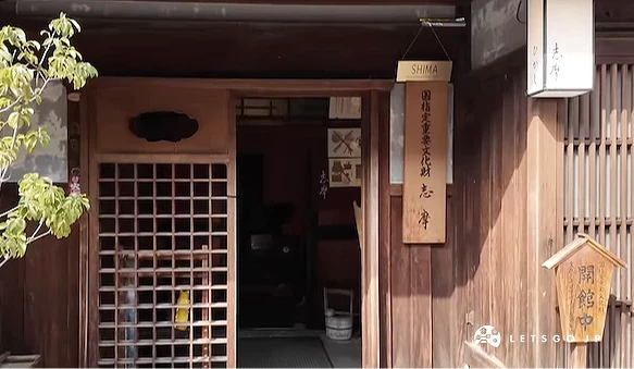 传统木造建筑立面,深褐木窗与格栅门扇古朴,招牌与盆栽点缀,日式古街风情