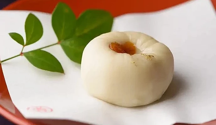 白色大福置于红盘,绿叶装饰点缀,传统日式点心精致优雅。